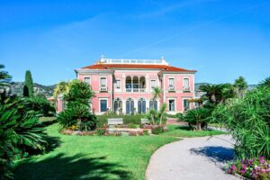 A large pink mansion with a manicured garden.