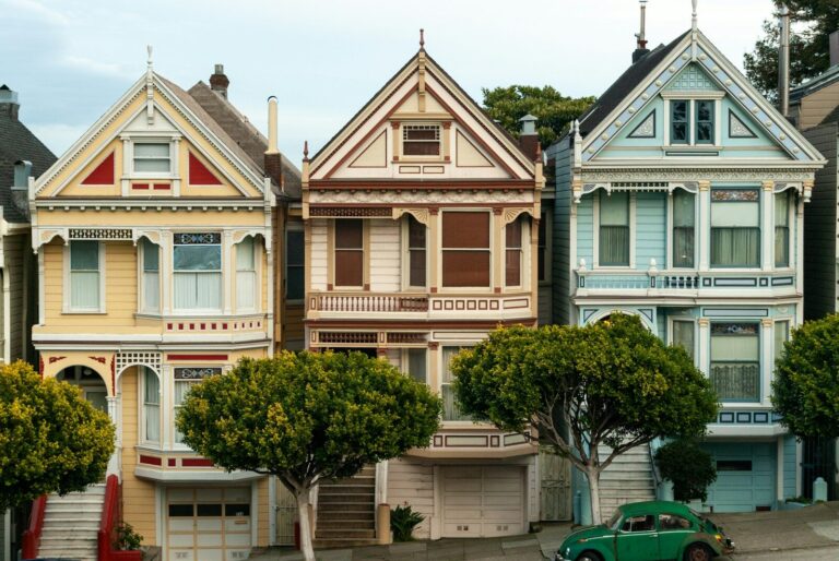 Row of colorful victorian houses with green car.