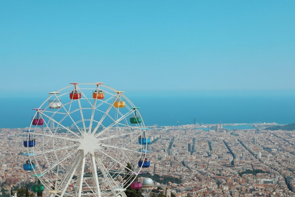 photography of ferris wheel and buildings beside seashore during daytime
